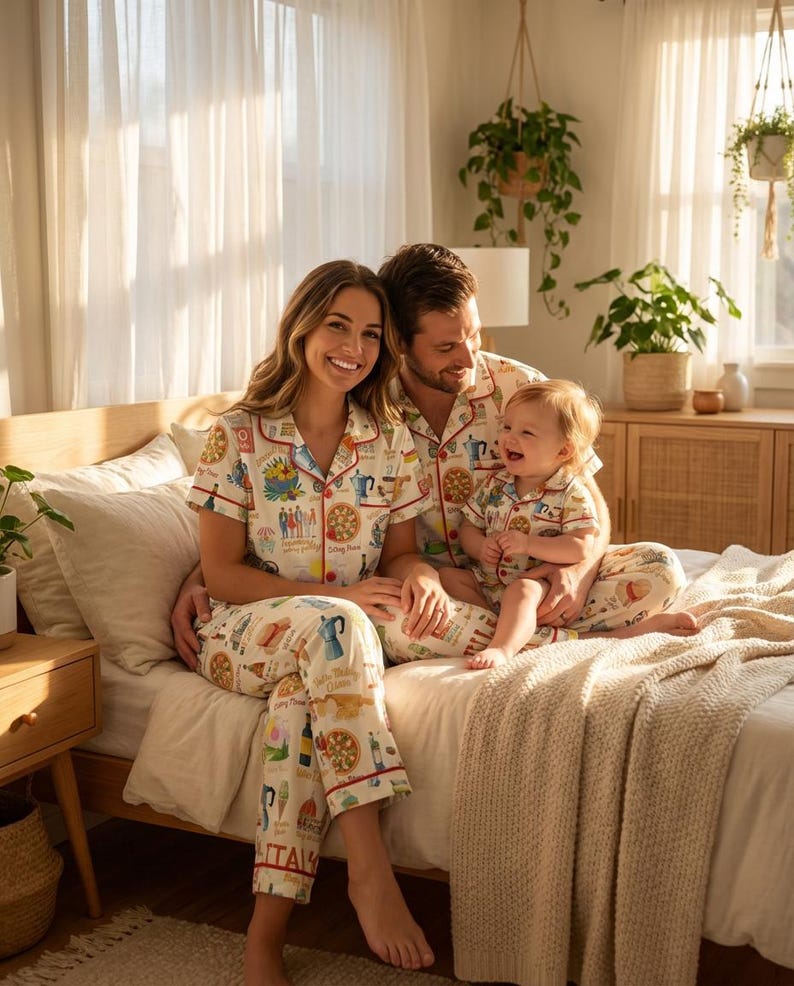K&ouml;nnte beinhalten: Passende Familien-Pyjama-Sets mit italienischem Thema. Die wei&szlig;en Pyjamas zeigen farbenfrohe Illustrationen italienischer Speisen und Symbole. Die Sets umfassen kurz&auml;rmelige Hemden und Hosen mit rotem Besatz. Eine dreik&ouml;pfige Familie tr&auml;gt die Pyjamas auf einem Bett.
