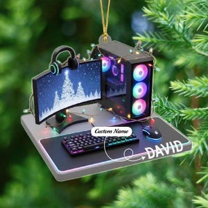 May include: A gaming PC Christmas ornament with a monitor displaying a winter scene, keyboard, mouse, and headphones. The ornament has the name "DAVID" and the words "Custom Name" on it. The PC case has colorful lights.