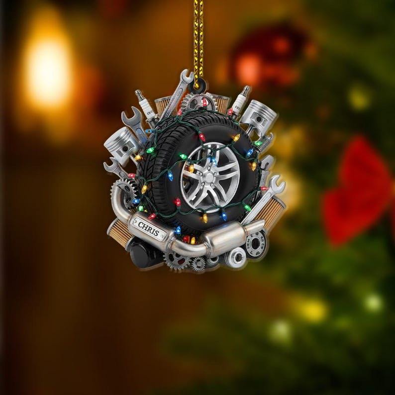 May include: A Christmas ornament featuring a car tire with a silver rim, surrounded by tools, pistons, and gears. The tire is wrapped with colorful Christmas lights. The name "CHRIS" is printed on a silver plate.