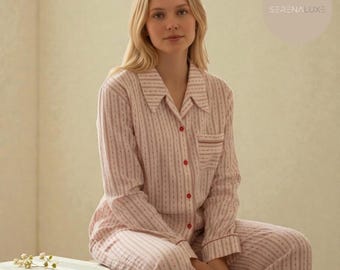 May include: Pink striped pajama set with red accents. The long-sleeved top has a button-down front and a chest pocket. The matching pants complete the set. The pajamas are made of a soft, comfortable material.