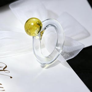 Denna ring har en klar glasrem med en gul klotaccent.
