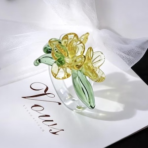 Anillo de cristal artesanal con flor amarilla y hojas verdes, joyería de borosilicato trabajada a fuego.