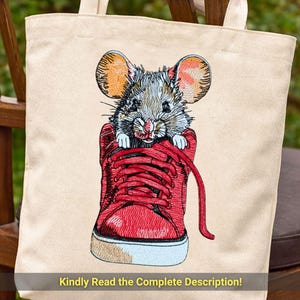 Puede incluir: Bolso tote beige con un diseño bordado de un ratón asomando por una zapatilla roja. El ratón tiene pelaje gris y marrón con grandes orejas naranjas. La zapatilla tiene suelas blancas y ribete azul. El texto en la parte inferior dice: ¡Lea atentamente la descripción completa!
