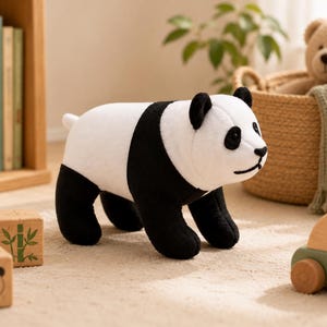May include: A plush panda toy featuring a white body with black limbs, black ears, and black patches around the eyes. The stuffed animal is depicted in a standing position with a soft, textured fabric finish and a simple stitched facial expression.