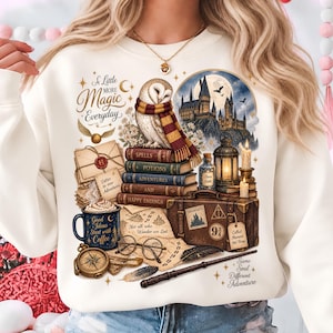 May include: A cream-colored sweatshirt featuring a graphic print of a barn owl wearing a striped scarf, a stack of books, a suitcase, a lantern, a coffee mug with text, glasses, a compass, a quill, and a castle under a full moon.
