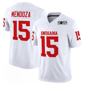 May include: White football jersey with red lettering and numbers. The jersey features "INDIANA" and the number "15" on the front, and "MENDOZA" and "15" on the back. The year "2026" is printed on the upper chest.