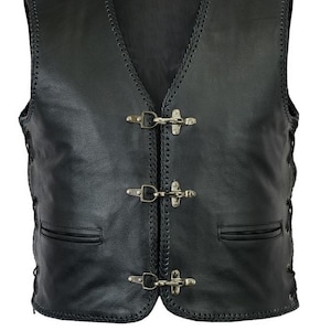 May include: A black leather waistcoat featuring a braided edge trim along the neckline and front opening. The garment fastens with three silver-toned metal hook-and-loop clasps. It includes two horizontal slit pockets and side lacing details.
