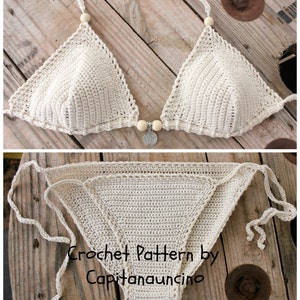 May include: A crocheted bikini top and bottom in a cream color. The top has a triangle shape with a decorative bead and charm in the center. The bottom is a simple triangle shape with ties on the sides. The bikini is laid out on a wooden surface.