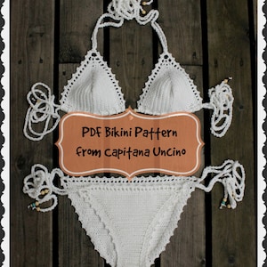 May include: White crochet bikini top and bottom with a brown sign that says "PDF Bikini Pattern from Capitanana Uncino".