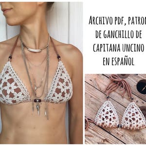 May include: A crochet bikini top with a floral pattern. The top is white with brown accents. The image also includes text that reads "ARCHIVO PDF, PATRON DE GANCHILLO DE CAPITANA UNCINO EN ESPAÑOL".