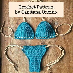May include: Teal crochet bikini set with cream ties. The top has triangle cups with a scalloped edge, and the bottoms have a similar design. The text "Crochet Pattern by Capitana Uncino" is displayed at the top.