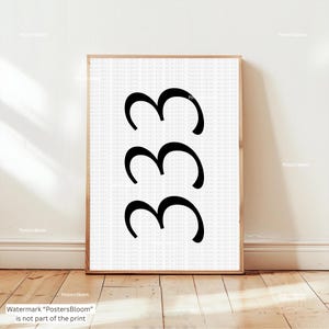 Può includere: Una stampa incorniciata con il numero "333" in grassetto, nero, su sfondo bianco. L'opera è presentata in una cornice di legno chiaro e poggia su una parete bianca e un pavimento in legno.