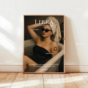 May include: A framed art print featuring a woman in a bathtub, wearing sunglasses and a black top, with a towel on her head. The print has the word "LIBRA" and the dates "SEPTEMBER 23 - OCTOBER 22". Additional text includes "CHARMING, BALANCED, ROMANTIC, DIPLOMATIC, FAIR, GRACEFUL".