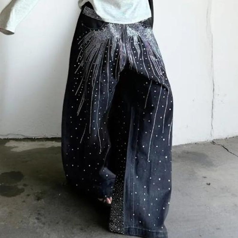 Unisex Rhinestone Pants | Wide Leg Studded Jeans | Glitter Streetwear Fashion Bottoms
.
Wide-leg black pants decorated with cascading rhinestones and glitter stud details shown in a studio setting.