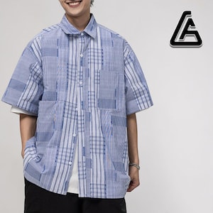 Op de afbeelding: Blauw en wit shirt met korte mouwen en een patchwork-ontwerp. Het shirt heeft een kraag, een knoopsluiting en een wit ondershirt. Het shirt heeft een mix van verticale strepen en ruitpatronen.