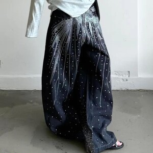 Unisex Rhinestone Pants | Wide Leg Studded Jeans | Glitter Streetwear Fashion Bottoms
.
Wide-leg black pants decorated with cascading rhinestones and glitter stud details shown in a studio setting.