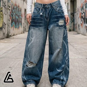 May include: Wide-leg blue denim jeans with distressed detailing and white decorative patterns. The jeans have a high waist and a relaxed fit. The jeans have a ripped knee detail. The jeans are suitable for casual wear.