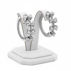 May include: A trio of cream-glazed ceramic mugs with a speckled finish. Each mug is adorned with a hand-painted design: a blue and green leaf, a yellow flower, and a red berry. The mugs have a simple, modern design.