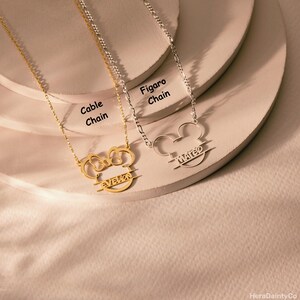 Peut inclure: Deux colliers personnalis&eacute;s avec un motif de t&ecirc;te de Mickey Mouse. L'un est dor&eacute; avec une cha&icirc;ne c&acirc;ble et le nom "EVELON". L'autre est argent&eacute; avec une cha&icirc;ne Figaro et le nom "MATEO".