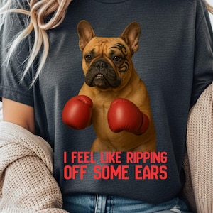 Pode incluir: Camiseta cinza escuro com um cão boxer com luvas de boxe vermelhas e uma tatuagem tribal. O texto vermelho diz "I FEEL LIKE RIPPING OFF SOME EARS". Uma camiseta de estilo casual.