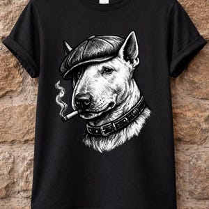 May include: Black t-shirt with a monochrome illustration of a Bull Terrier wearing a flat cap and a collar, smoking a cigarette. The dog's portrait is the central design element, creating a striking visual.