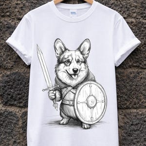 Può includere: T-shirt bianca con un'illustrazione in bianco e nero di un cane Corgi vestito da guerriero. Il cane tiene una spada e uno scudo, con una cintura. Il design è stampato su una t-shirt bianca, adatta per l'uso quotidiano.