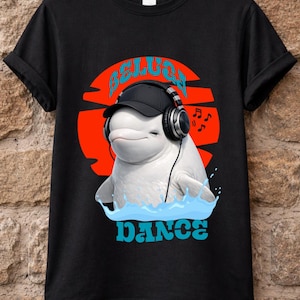 May include: Black t-shirt featuring a white beluga whale wearing a black cap and headphones, set against a red and orange sunset. The word "BELUGA" is above the whale, and "DANCE" is below, in blue.