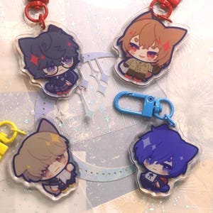 Peut inclure: Quatre porte-clés en acrylique représentant des personnages de style anime avec des oreilles de chat. Chaque porte-clés présente un design de personnage différent avec des couleurs de cheveux et des tenues variées. Les porte-clés sont attachés à des fermoirs rouges et jaunes et à un mousqueton bleu.