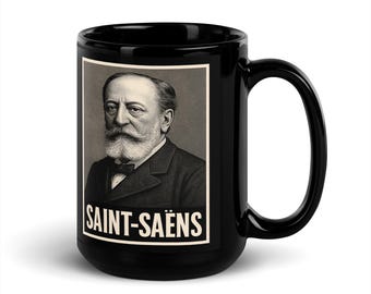 Op de afbeelding: Zwarte keramische mok met een portret van Camille Saint-Saëns in een zwart-wit kader. De mok heeft een grote handgreep en de naam "SAINT-SAËNS" is in witte letters onder het portret gedrukt.