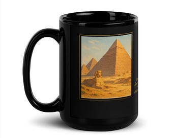 May include: A black ceramic mug featuring a square graphic print of the Great Sphinx and the Giza pyramids in Egypt under a clear sky. The image is framed with a thin gold border, and there is partially visible text in gold script on the right side.