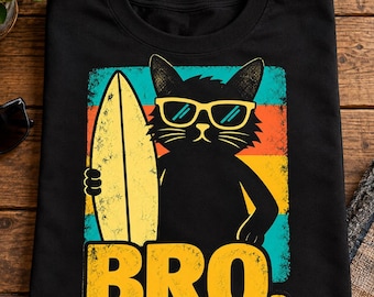 Puede incluir: Una camiseta negra de manga corta con un gráfico de un gato negro que lleva gafas de sol amarillas y sostiene una tabla de surf amarilla. El fondo consta de franjas horizontales de color verde azulado, naranja y amarillo. El texto BRO está impreso en amarillo.