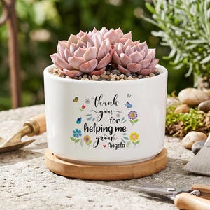 May include: A white ceramic planter with a bamboo saucer containing a pink succulent. The planter features the text "thank you for helping me grow" with colorful floral and butterfly illustrations and the name "Angela" in black script.