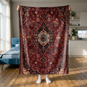 Könnte beinhalten: Eine rechteckige Wohndecke mit tiefrotem Hintergrund und einem komplexen, symmetrischen Muster in Schwarz, Creme und Blau. Das Design umfasst komplizierte florale und geometrische Motive, die um ein zentrales Medaillon angeordnet sind.
