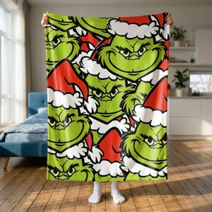 Könnte beinhalten: Eine weiche Fleecedecke mit einem sich wiederholenden Muster der grünen Grinch-Figur, die eine rot-weiße Weihnachtsmütze trägt. Das Design zeigt mehrere Nahaufnahmen des Gesichts der Figur mit verschiedenen Gesichtsausdrücken.