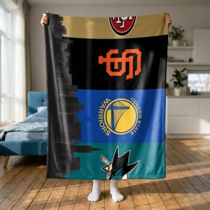 Könnte beinhalten: Eine rechteckige Fleecedecke mit einer vertikalen schwarzen Silhouette einer Skyline auf der linken Seite. Die Decke ist in vier horizontale Farbbänder unterteilt, die die Logos der San Francisco 49ers, San Francisco Giants, Golden State Warriors und San Jose Sharks zeigen.