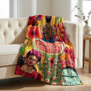 Może przedstawiać: Koc z kolorową ilustracją Fridy Kahlo, czarnego kota, kaktusów z różowymi kwiatami i kawałka arbuza. Tekst zawiera napisy Viva La Vida, Frida Kahlo, Coyoacan, 1954, Mexico oraz Soy Mi Propia Musa na tle o bardzo żywych barwach.