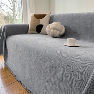 May include: A set of three ceramic mugs with a speckled, matte finish. Each mug features a different color: light blue, cream, and gray. The mugs have a simple, modern design and a comfortable handle.