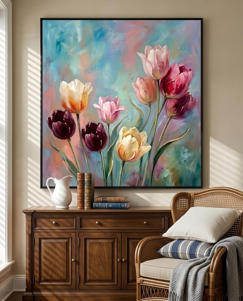 May include: A framed oil painting featuring a vibrant bouquet of tulips in shades of pink, red, yellow, and purple. The flowers are set against a soft, blended background of blue, pink, and green hues. The painting is displayed above a wooden cabinet.
