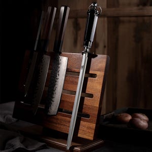 Puede incluir: Un bloque de cuchillos de madera con varios cuchillos y un afilador. Los cuchillos tienen mangos de madera oscura y hojas plateadas. El afilador tiene un mango negro y una varilla plateada. El bloque es de madera oscura.