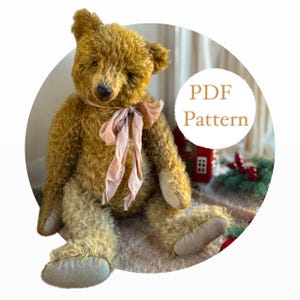 May include: A handmade, golden-brown teddy bear with a soft, textured appearance. The bear has a pink ribbon tied around its neck and light-colored paws. The image includes the text "PDF Pattern" in a white circle, suggesting a pattern for creating similar bears.