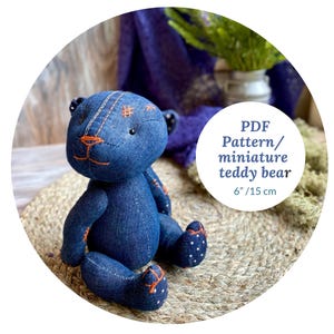 May include: A handmade denim teddy bear, approximately 6 inches (15 cm) tall, with orange stitching details. The bear has black button eyes and polka dot accents on its feet. The image includes text that reads "PDF Pattern/ miniature teddy bear".