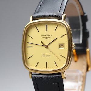 May include: A Longines quartz wristwatch featuring a square gold-tone case with rounded corners and a pale yellow dial. The watch has thin black hour markers, black hands, and a date window at the three o'clock position. It includes a black leather strap.