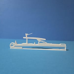 May include: A white, minimalist boat model with detailed lines and a sleek design. The model features a cabin, a radar mast, and a streamlined hull, set against a blue background. The boat's design suggests a focus on nautical themes and maritime decor.