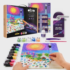 Peut inclure: Un kit d'art sensoriel DIY avec un paysage coloré. Le kit comprend une boîte, des tubes de peinture, des flacons de peinture, un pinceau et un accroche-porte violet avec l'inscription "IT'S ME TIME DO NOT DISTURB". L'œuvre d'art représente un phare et un coucher de soleil.