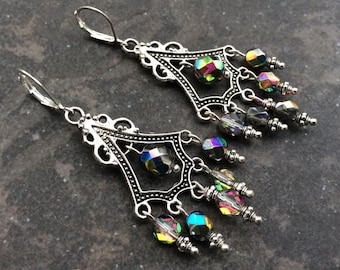 May include: Silver dangle earrings with iridescent crystal beads. The earrings feature a filigree design and are approximately 2 inches long.