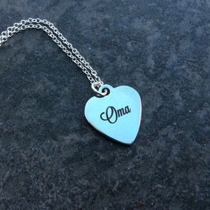 May include: A silver necklace with a heart-shaped pendant that says "Oma" on it.