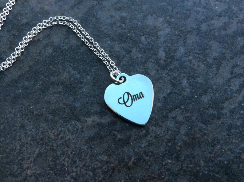 May include: A silver necklace with a heart-shaped pendant that says "Oma" on it.