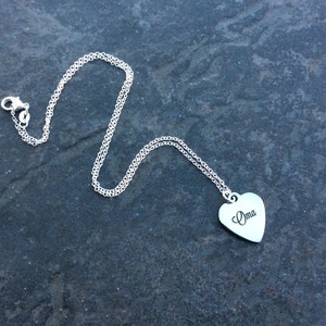 May include: A silver chain necklace with a heart-shaped pendant that says "Oma" on it.