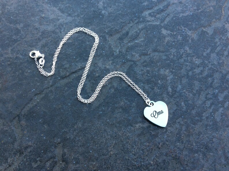 May include: A silver chain necklace with a heart-shaped pendant that says "Oma" on it.