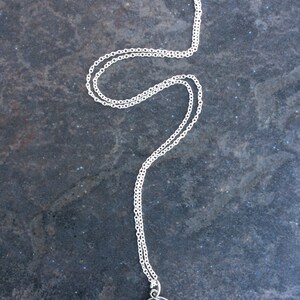 May include: A silver chain necklace with a round pendant featuring a silver image of a praying angel.